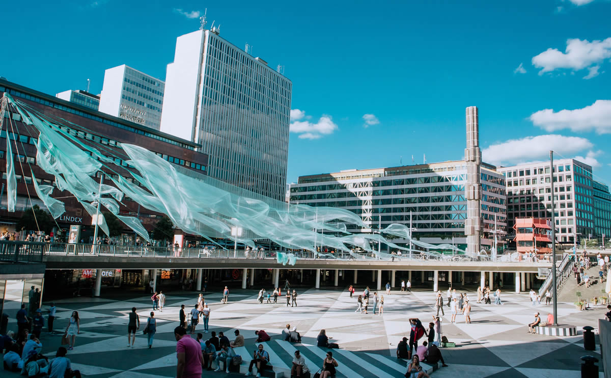Creative Cities, Stockholm, Sweden, city square with a flowing art installation and people enjoying the sunny day