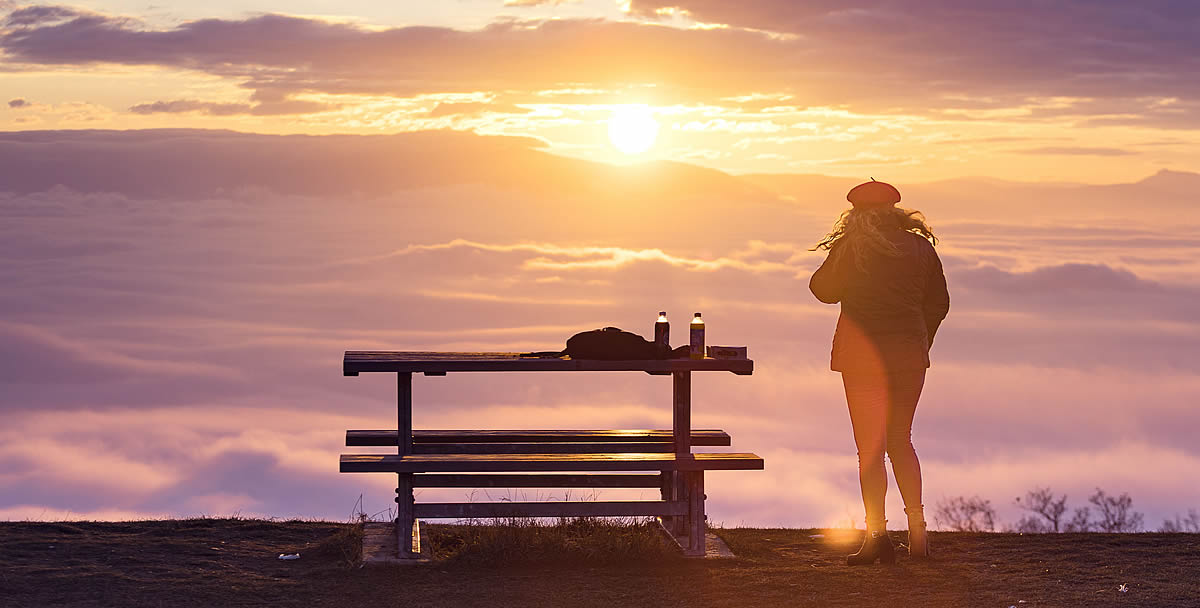 Gender Gap Bosnia and Herzegovina, Gender Equality, a woman stands by a picnic table watching a vibrant sunset over a sea of clouds