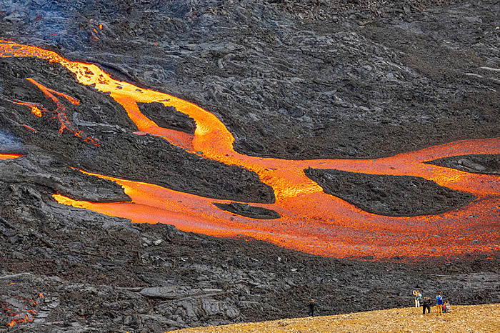 Iceland Global Development, lava flow captivating tourists at volcano