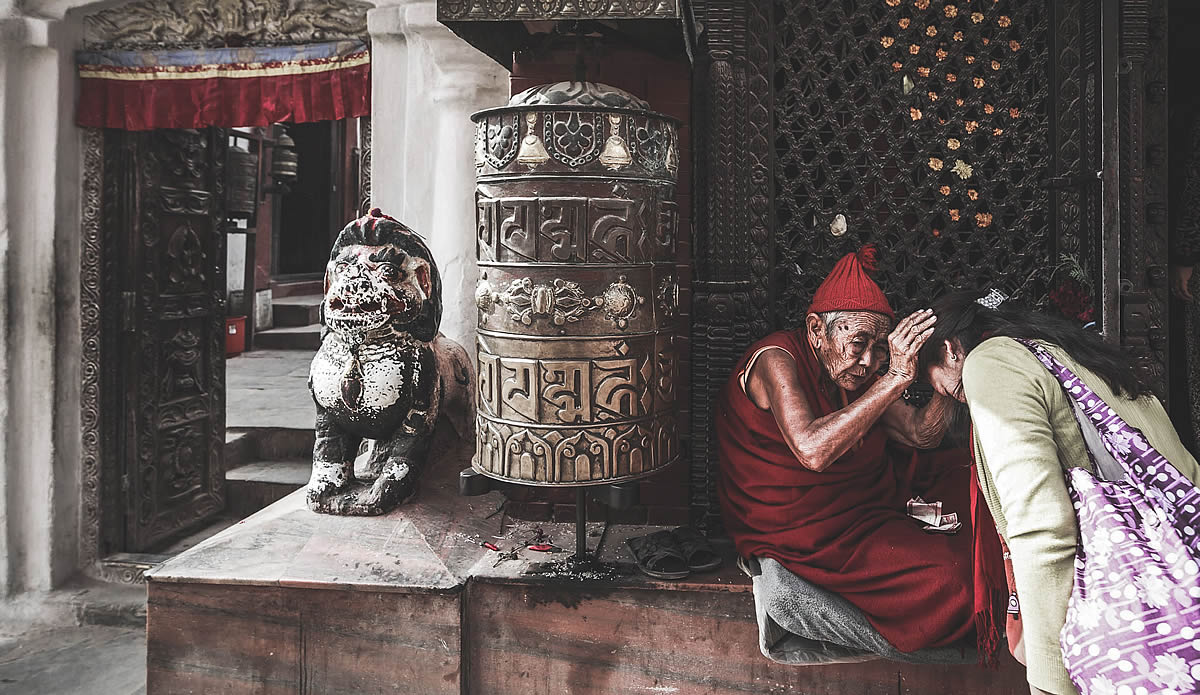 Nepal Global Development, monk performs a ritual with a visitor at an ancient temple shrine