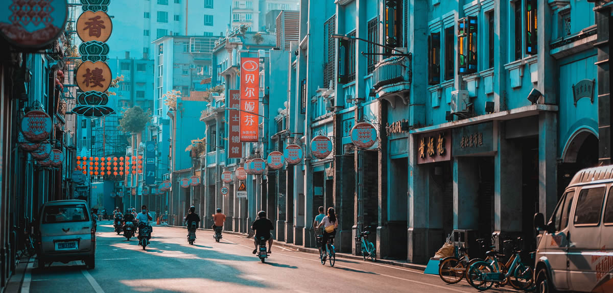VAWG China, Street scene in Guangzhou showcasing heritage architecture and daily life with cyclists and pedestrians