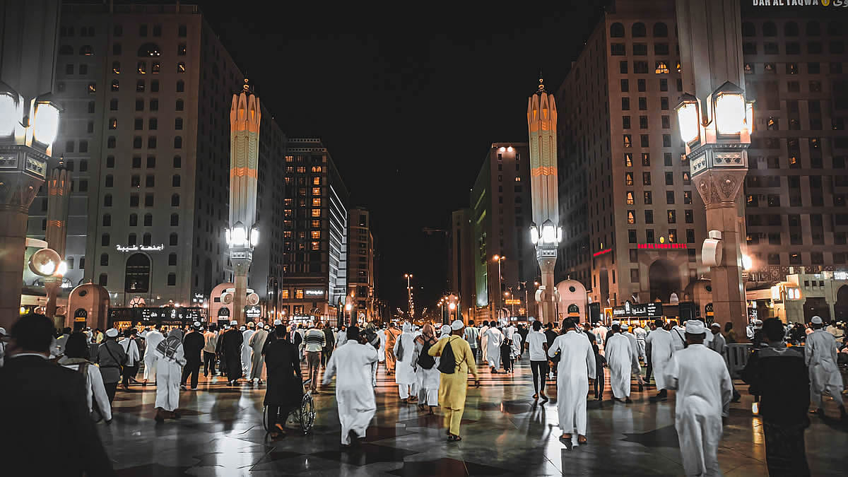 Gender Gap Saudi Arabia, A busy street in Medina, Saudi Arabia, filled with people under illuminated city lights at night.